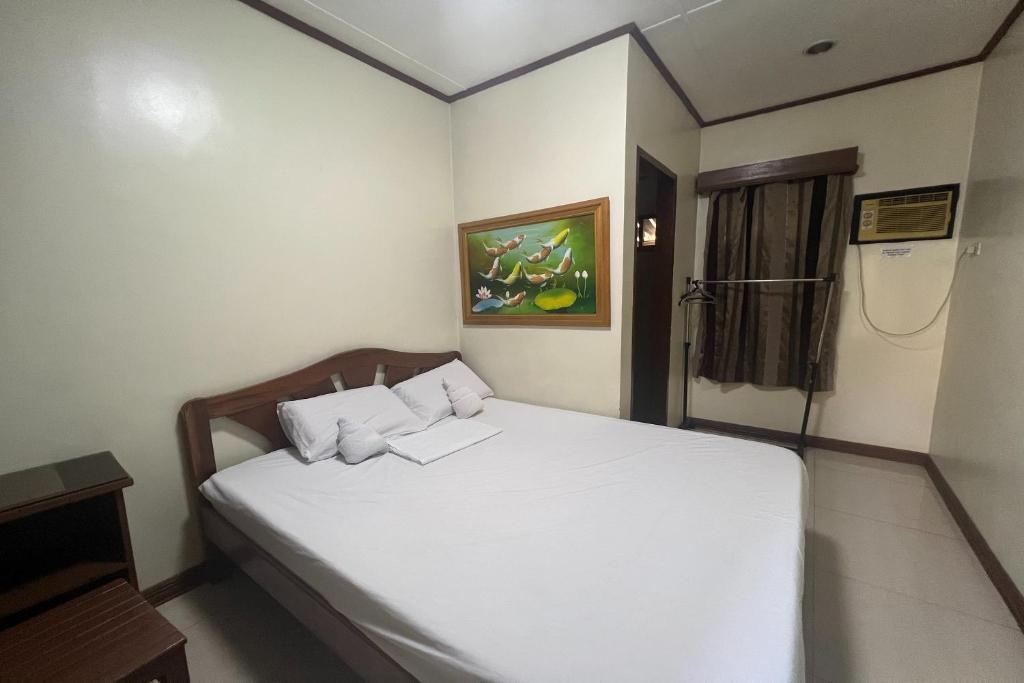 een slaapkamer met een wit bed in een kamer bij Tenzai Homestay in Puerto Princesa City