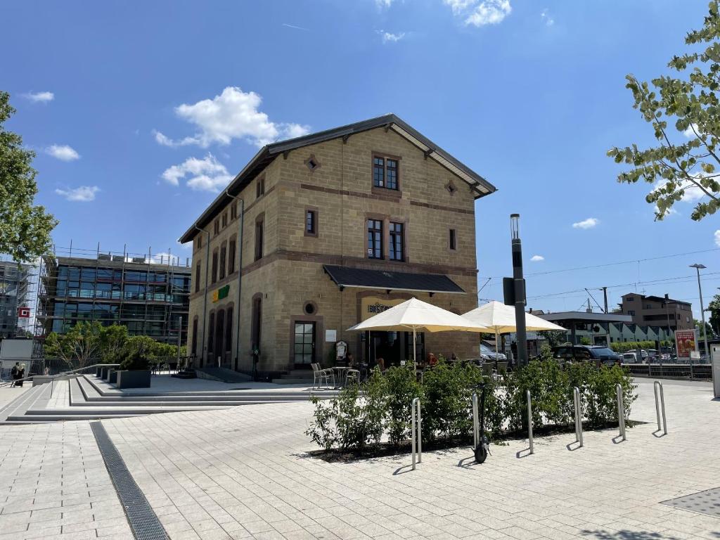 迪欽根的住宿－Hotel-am-Bahnhof Stuttgart-Ditzingen，一座古老的砖砌建筑,前面设有桌子和遮阳伞