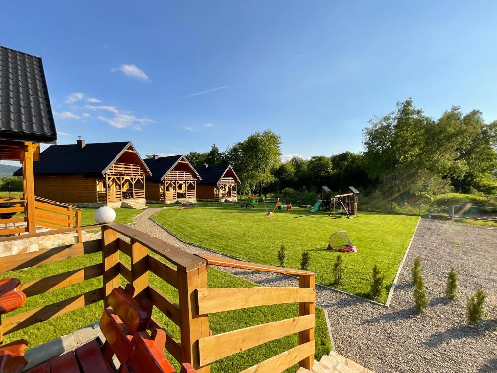 a yard with a fence and a park with houses at Domki Gaja in Wysowa-Zdrój