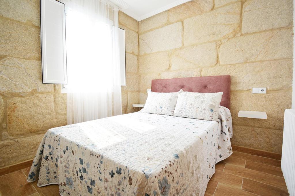 una camera con un letto in una stanza con un muro in pietra di Casa con jardín en Pontevedra a Pontevedra
