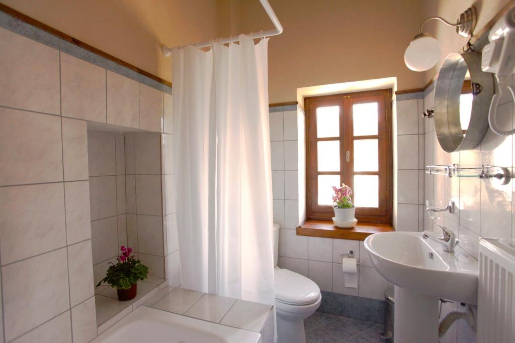 Baño blanco con aseo y lavamanos en Yono's Traditional House en Ano Ravenia