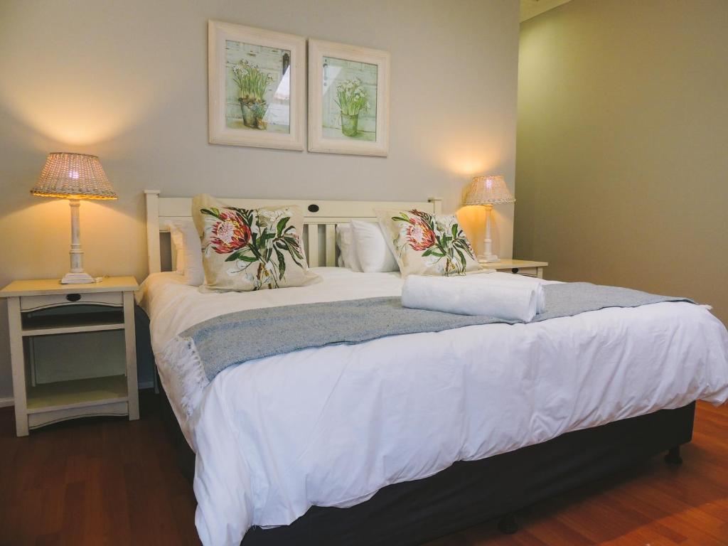 a bedroom with a large white bed with two lamps at 7 @ The Dunes in Plettenberg Bay