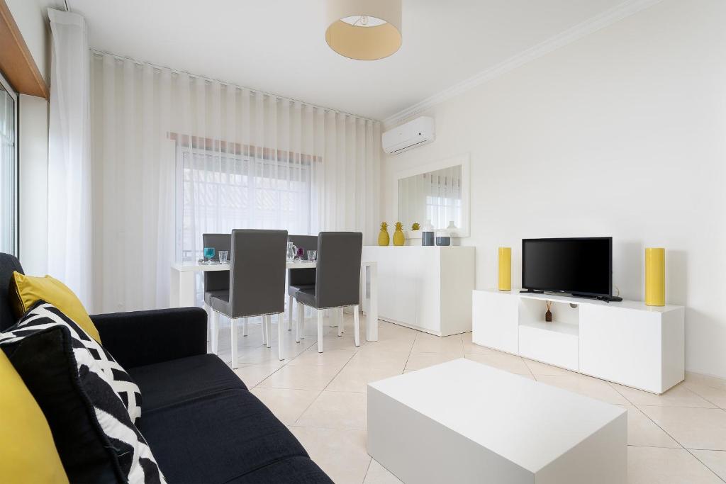 a white living room with a couch and a table at IsaBela Holidays in Olhos de Água