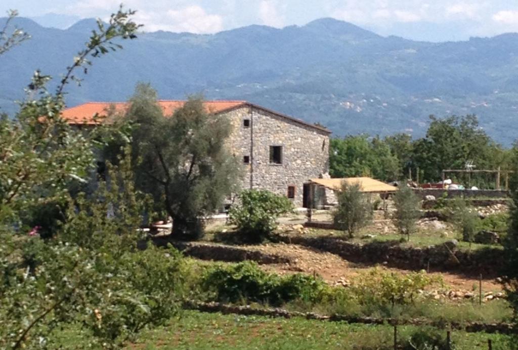 a stone house in a field with mountains in the background at B&B Oca Nera Lerici in Lerici