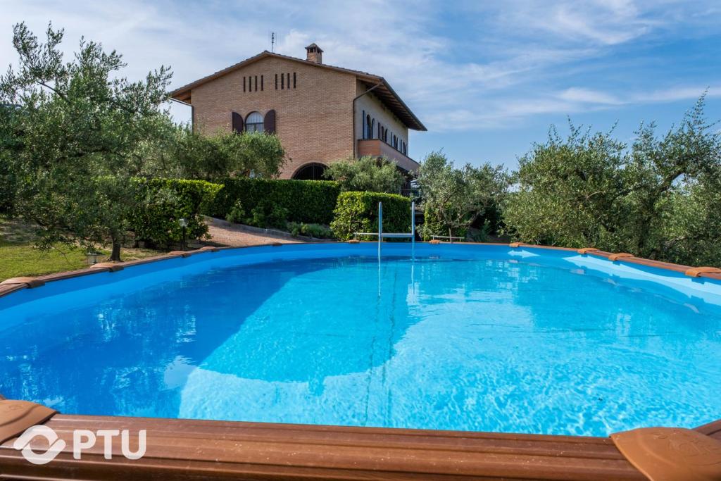 une grande piscine bleue devant une maison dans l'établissement PoloTuristicoUmbria Villa del Maestrale, à Pérouse