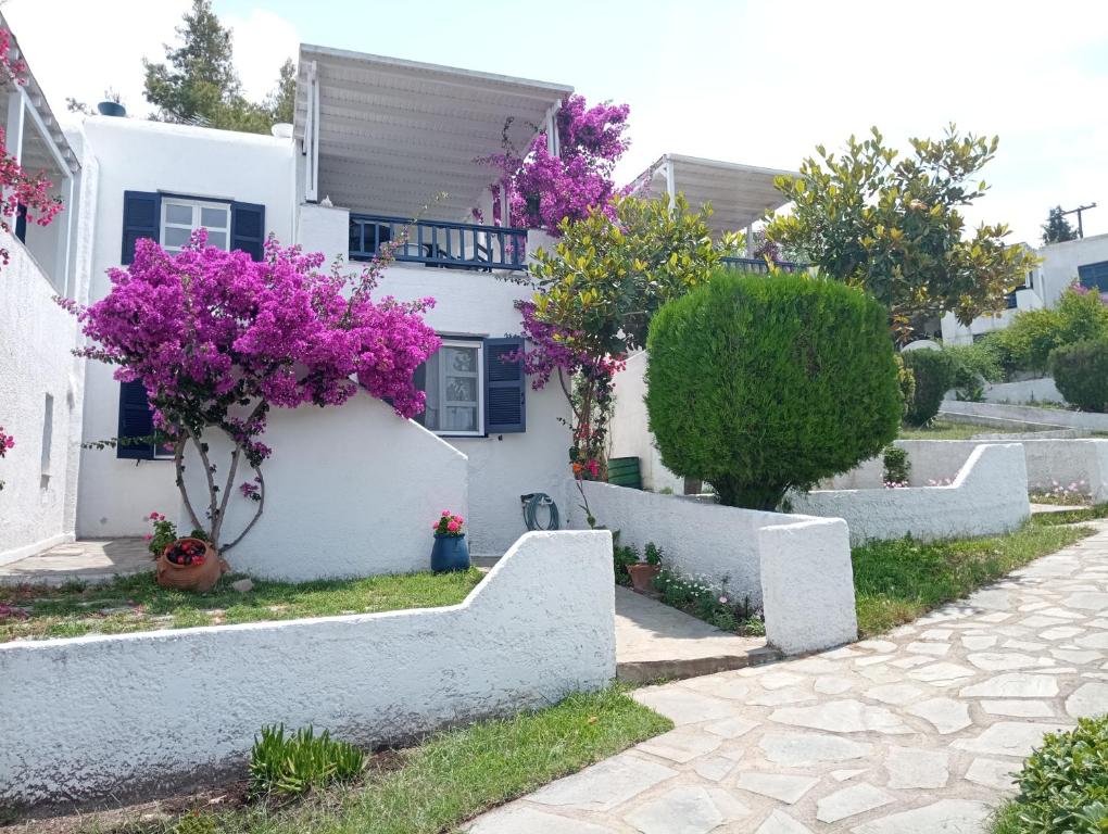 Una casa blanca con flores púrpuras a un lado. en Villa Danai, en Toroni