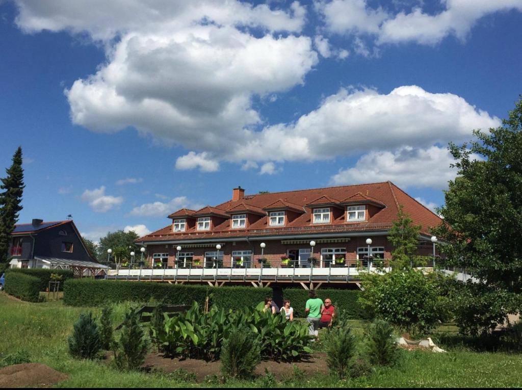 a group of people sitting in front of a large building at Hotel und Restaurant zum bunten Hirsch in Mirow