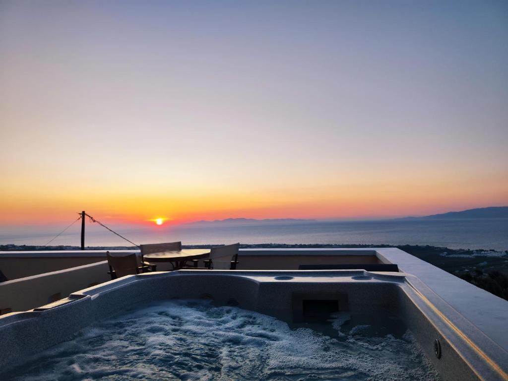 a hot tub on the roof of a house with a sunset at Panorama Oia Apartments in Oia