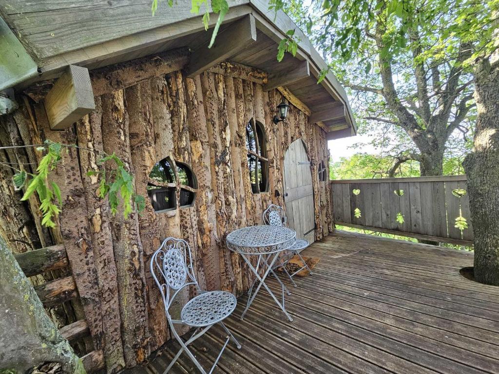 a log cabin with two chairs and a table on a deck at Au Refuge Des 3 Ours - Chambres d&#39;hôtes et cabanes in Essuiles-Saint-Rimault