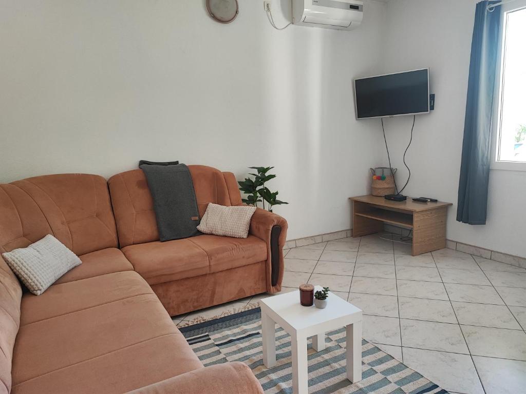 a living room with a brown couch and a tv at Apartments and Rooms Batoš in Zavala