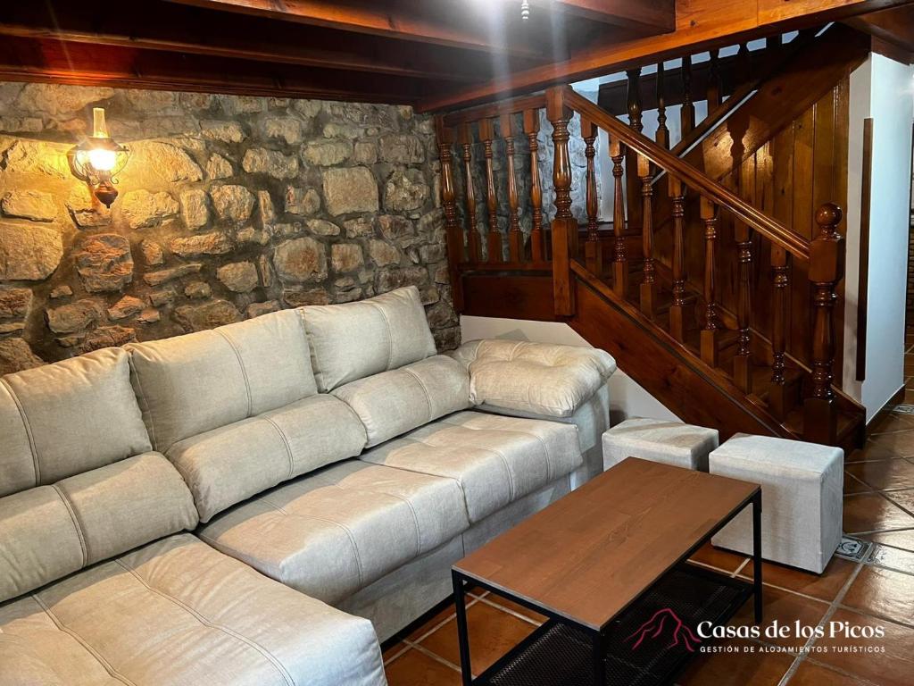 ein Wohnzimmer mit einem Sofa und einer Steinmauer in der Unterkunft Vivienda vacacional El Cau - Casas de Los Picos in Ruenes