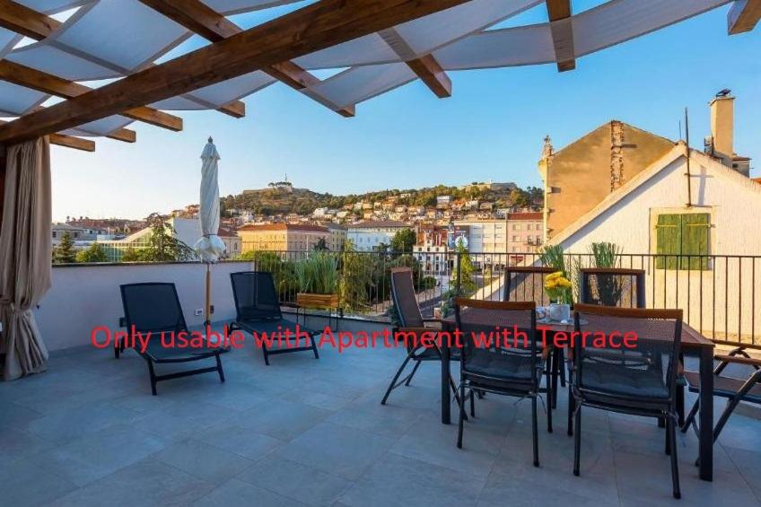 eine Terrasse mit einem Tisch und Stühlen auf dem Balkon in der Unterkunft Luxury apartments Azalea Šibenik in Šibenik