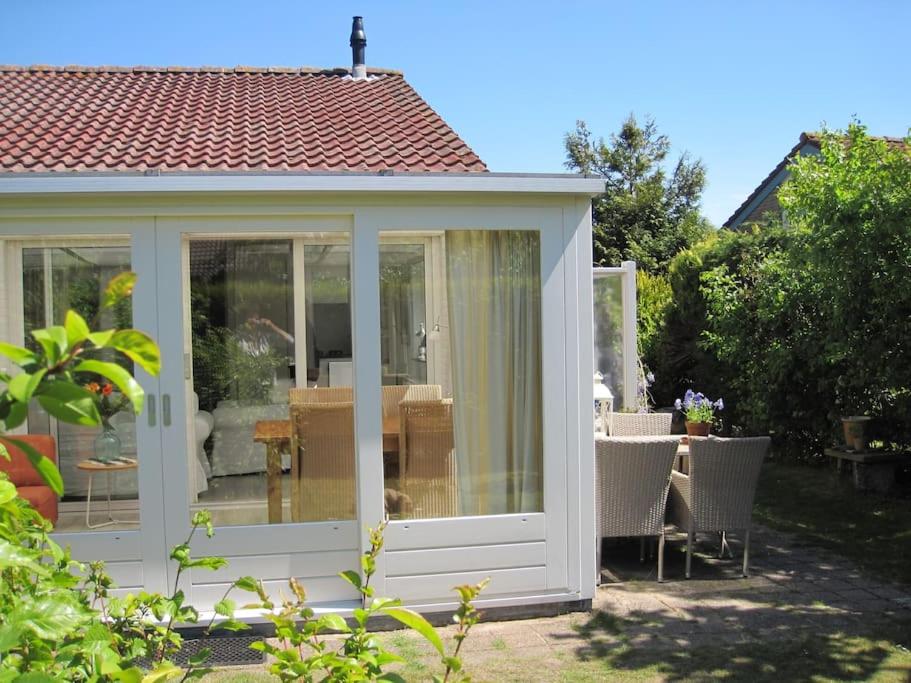 um jardim de Inverno branco com uma mesa e cadeiras num quintal em De Zeemeeuw em Egmond aan den Hoef