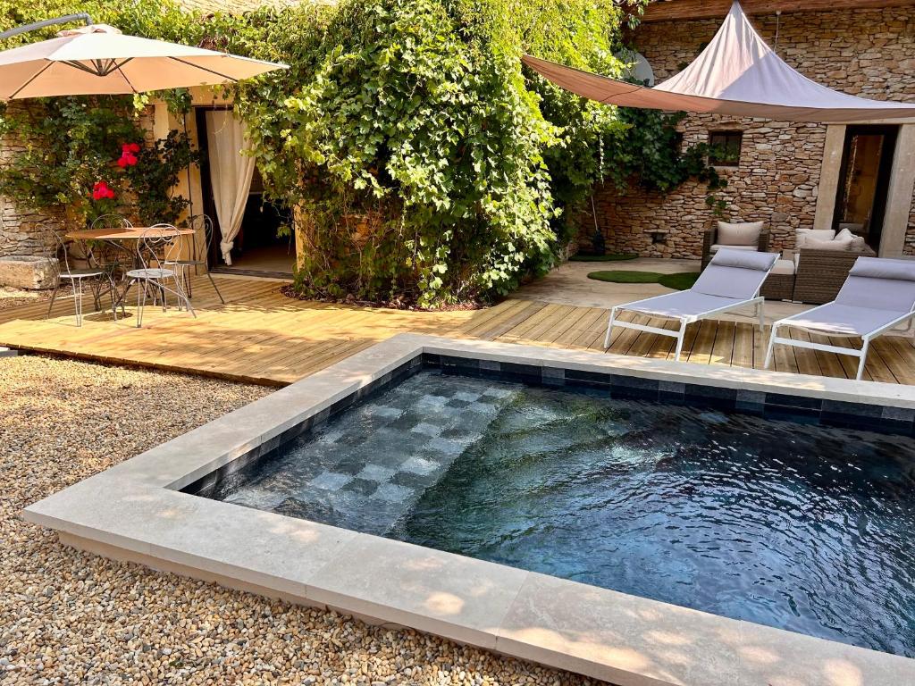 una piscina en un patio con sillas y sombrilla en Maison à Gordes dans le Lubéron, en Gordes