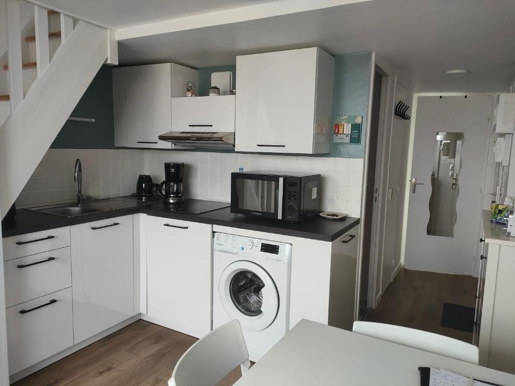 eine Küche mit einer Waschmaschine und einer Mikrowelle in der Unterkunft Ref 095 - Appartement pour quatre proche port Crouesty in Arzon