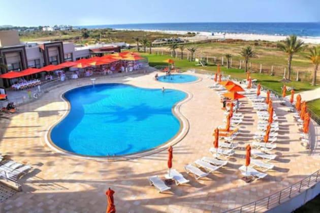 Blick auf einen Pool mit Stühlen und Sonnenschirmen in der Unterkunft Andalucia Bizerte plage et piscine in Bizerte