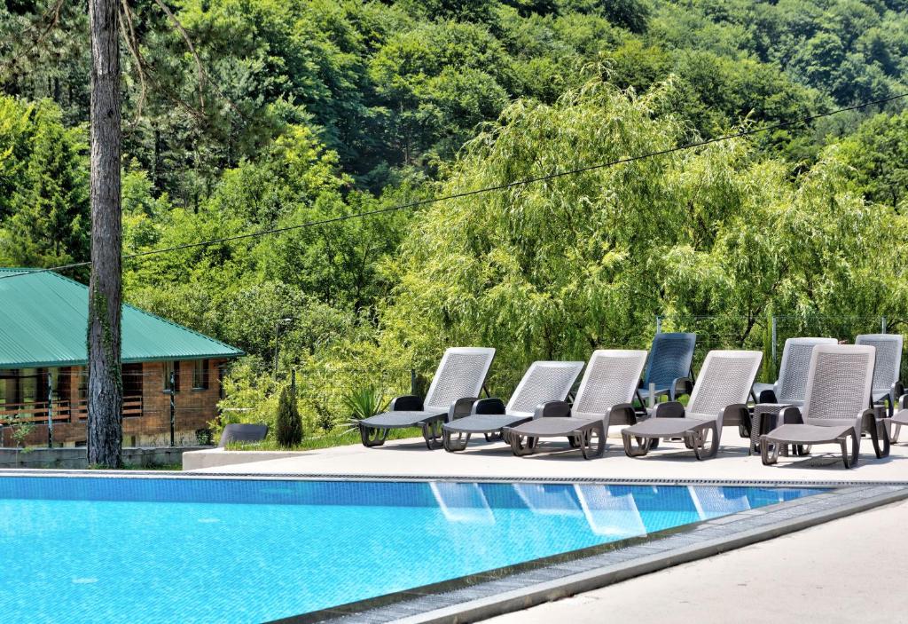 a row of lounge chairs next to a swimming pool at Vila Sunce Village Resort Konjic in Konjic