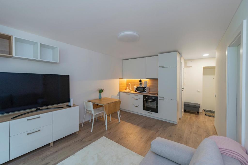 a living room with a large television and a kitchen at Convenient apartment with balcony by Polo Apartments in Kaunas