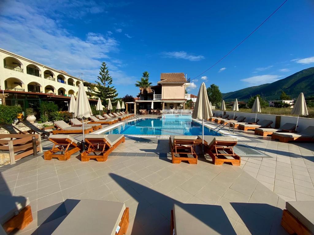 a hotel with a swimming pool with chairs and umbrellas at Roula Studios in Pigadhákia