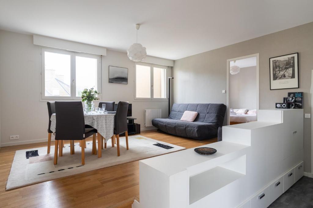 uma sala de estar com uma mesa e cadeiras e um sofá em Le Rez de Plage - Appt pour 4 vue mer et proche des plages em Saint Malo