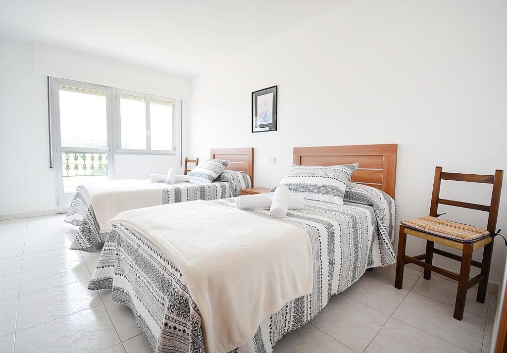 1 Schlafzimmer mit 2 Betten und einem Stuhl in der Unterkunft Apartamento Vistas Vilar in Sanxenxo