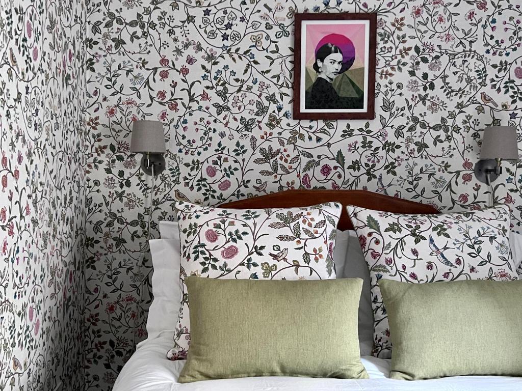 a bedroom with a bed with a flowery wallpaper at Cosy Weavers Cottage - Heart of Frome in Frome