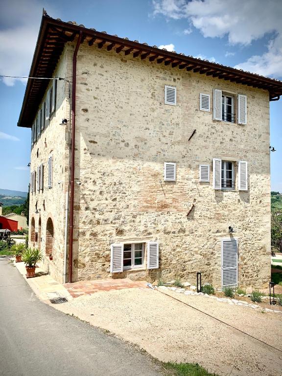 a large stone building with white windows and a street at The Loft By Birillo in Poggibonsi