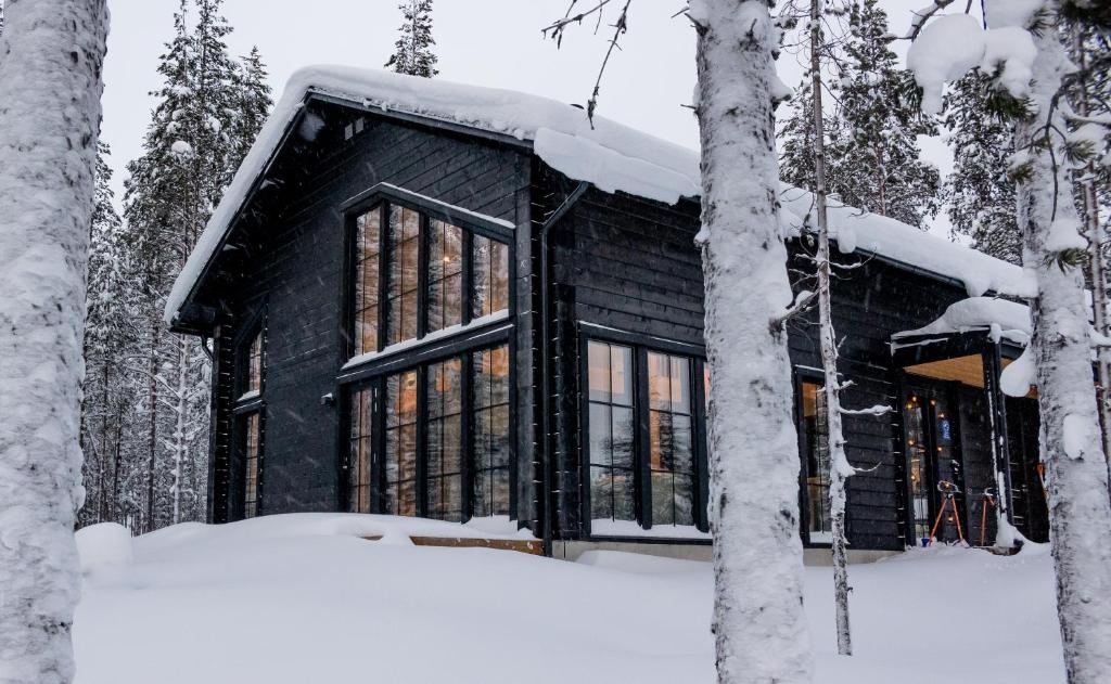 une cabine noire dans les bois dans la neige dans l'établissement Black Work Levi Aarni, à Kittilä