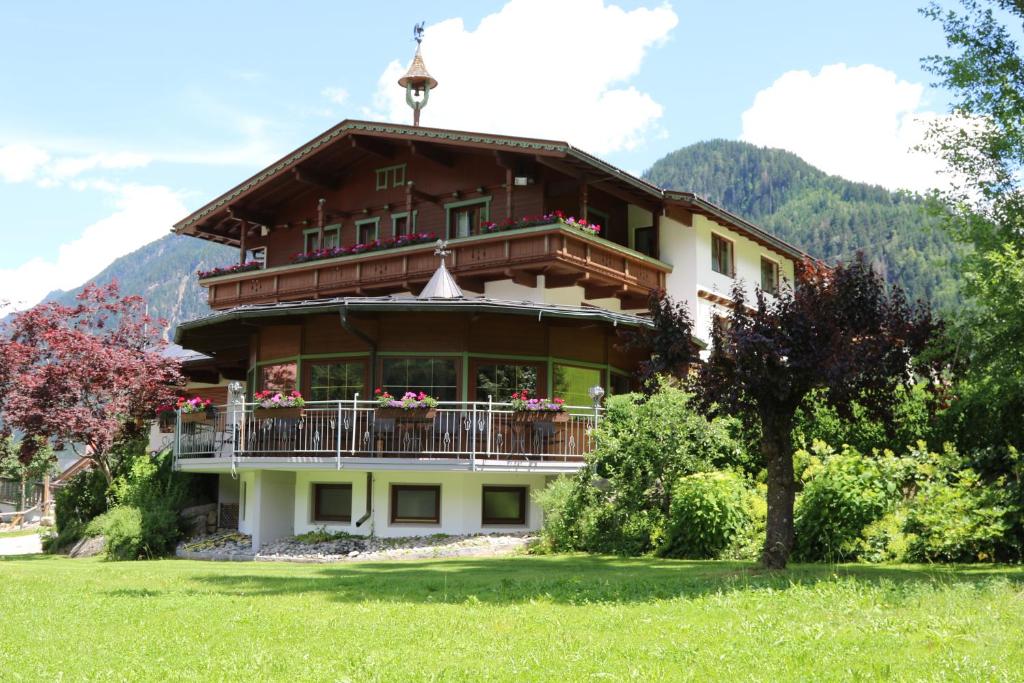a large house with a balcony and a mountain at Hotel Gasthof Stoanerhof in Mayrhofen