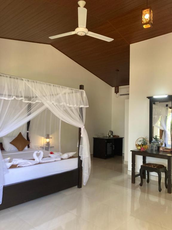 a bedroom with a bed with a canopy and a table at The View Hotel Sigiriya in Sigiriya