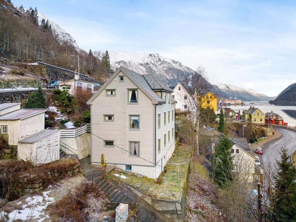 a white house on a hill with mountains in the background at Odda City Apartments in Odda