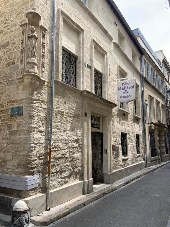 a building with a sign on the side of a street at Hôtel Le Médiéval Palais des Papes in Avignon