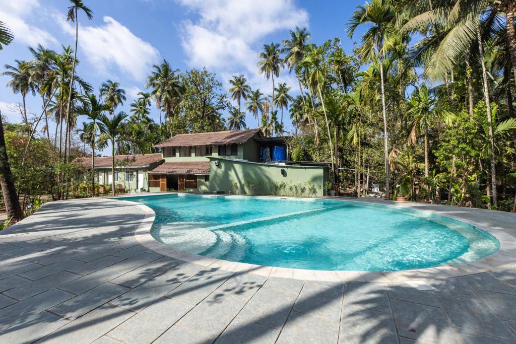 a swimming pool in front of a house with palm trees at Oceanature Alibaug in Alibaug
