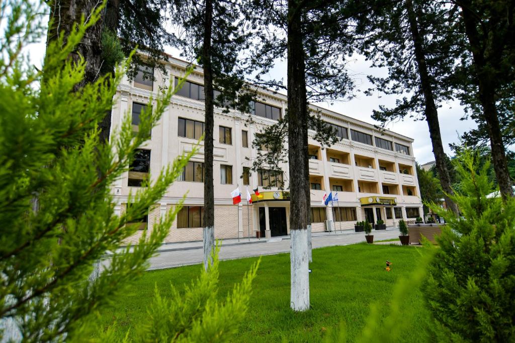un gran edificio blanco con árboles delante de él en Gelati Residence en Kutaisi