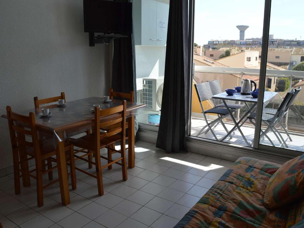 une salle à manger avec une table et des chaises et un balcon dans l'établissement Studio climatisé 4 couchages proche plage et commerces au Grau-du-Roi - FR-1-250-160, au Grau-du-Roi