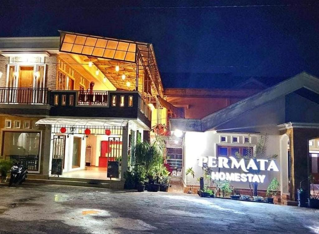 een gebouw met een bord aan de zijkant 's nachts bij Permata Homestay Kotamobagu Mitra RedDoorz in Poyowa-besar
