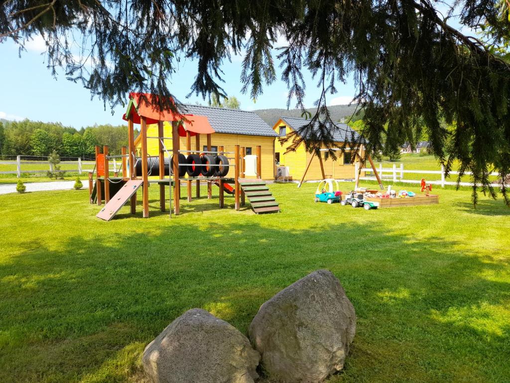 a playground with a slide and rocks in the grass at Sudecka Wiata-Domki in Głuszyca