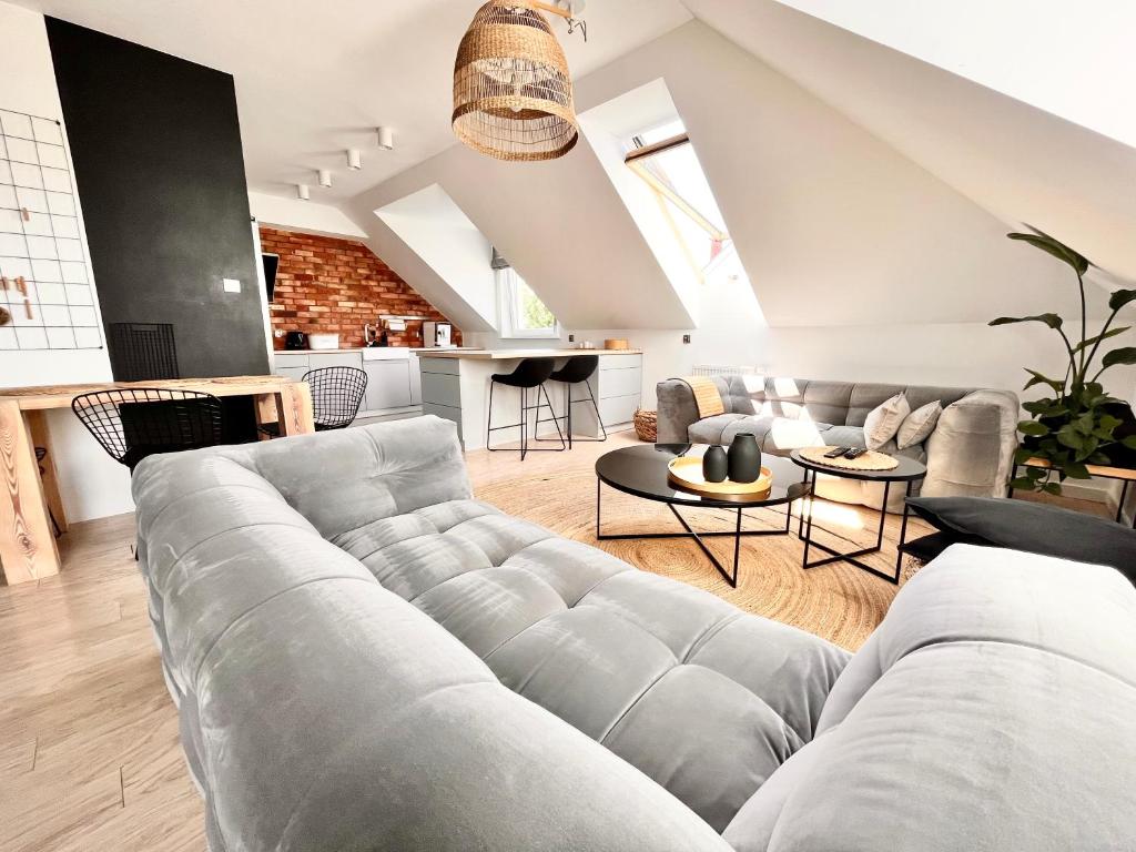 a living room with a large gray couch and tables at Ach to tu Apartament in Ostróda