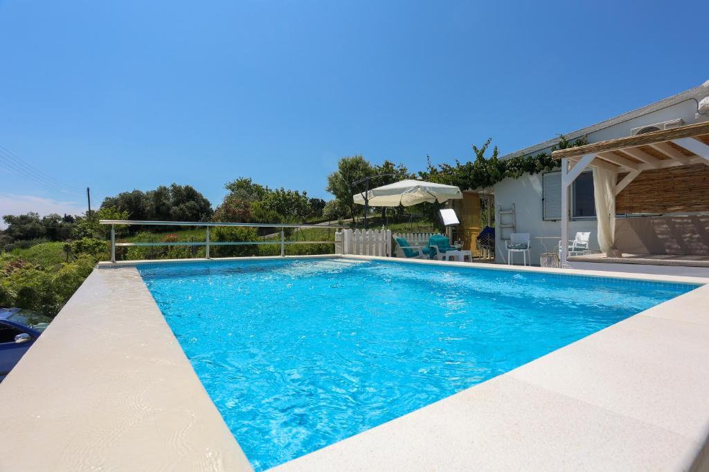 a swimming pool with blue water in a house at Summer House in Corfu Town in Mantoúkion