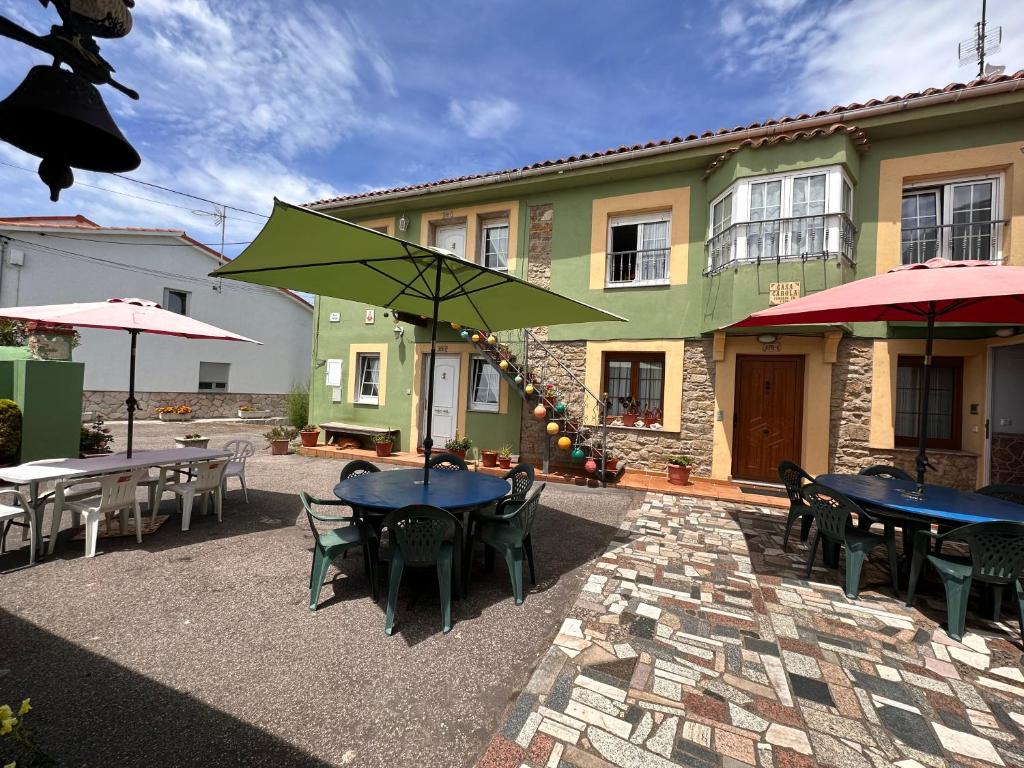 eine Terrasse mit Tischen und Sonnenschirmen vor einem Gebäude in der Unterkunft Apartamentos casa Carola in Viodo