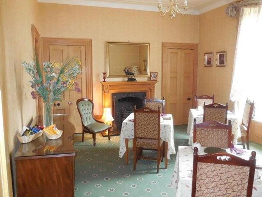 sala de estar con mesa, sillas y chimenea en Butlers Guest House, en Aberdeen