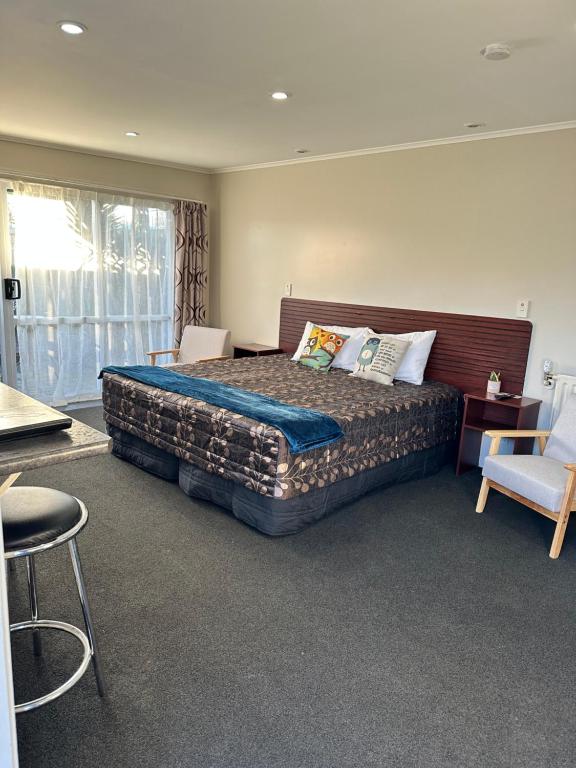 a bedroom with a large bed and a chair at Red Rock Thermal Motel - Mineral Pool in Rotorua