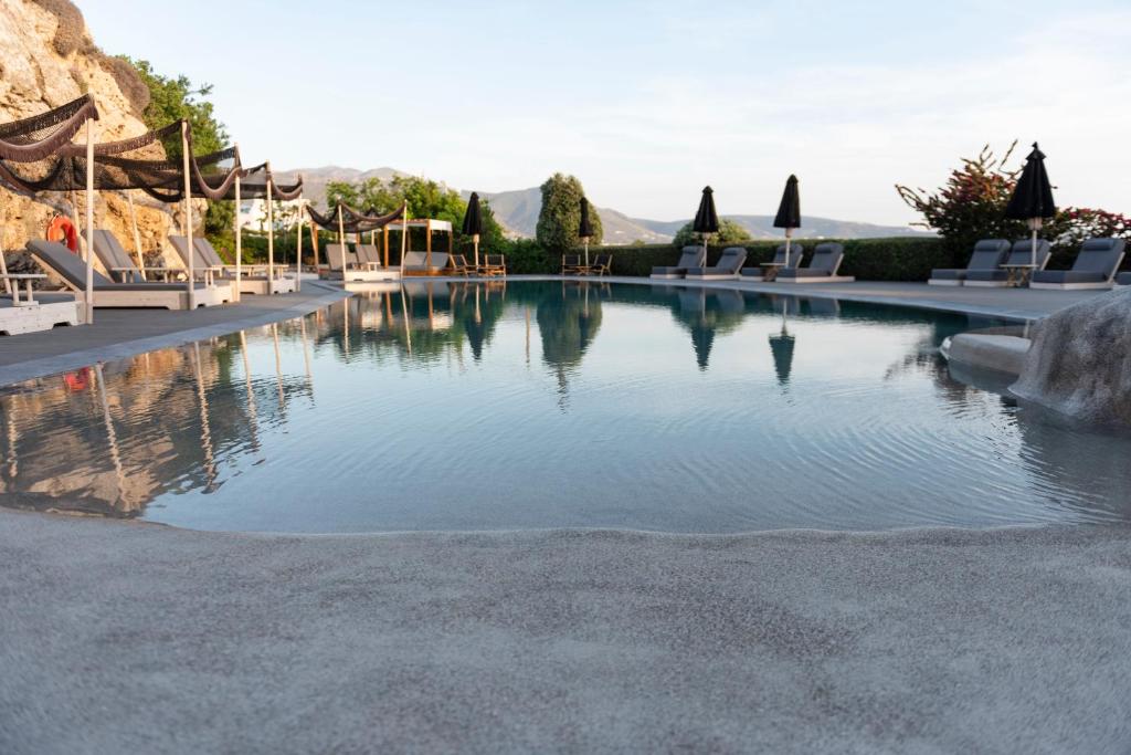 a pool at a resort with chairs and trees at Paros Agnanti Resort & Spa in Parikia