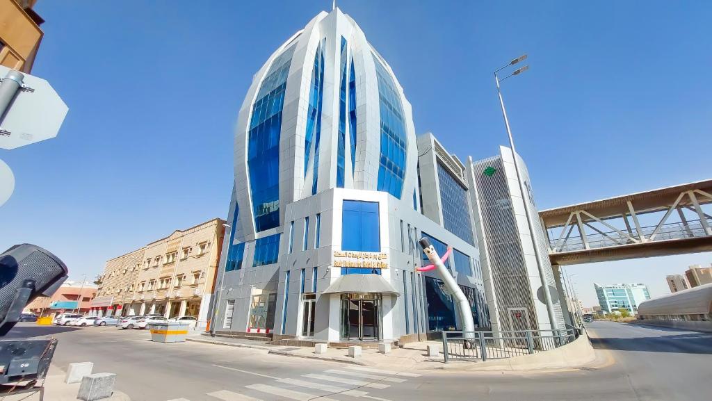 un grand bâtiment en verre sur le côté d'une rue dans l'établissement Golden Dune Hotel Almalaz, à Riyad