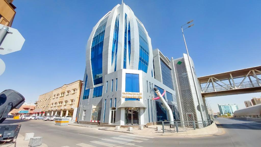 um edifício de vidro alto ao lado de uma rua em Golden Dune Hotel Almalaz em Riade