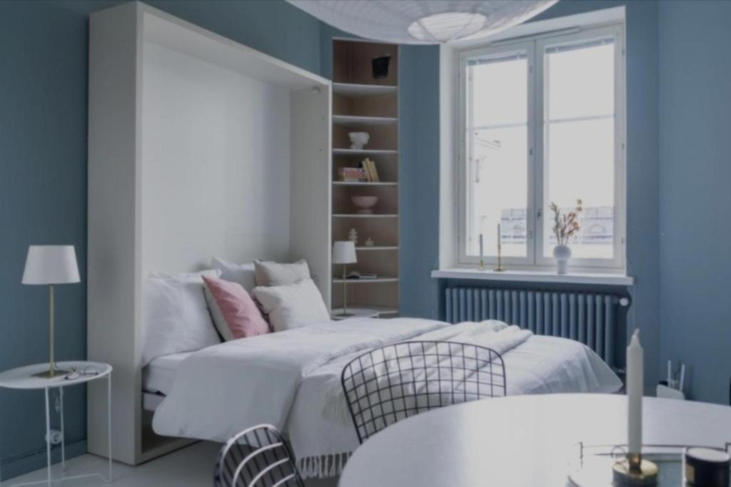 ein Schlafzimmer mit einem weißen Bett und einem Fenster in der Unterkunft Beautiful studio apartment in the heart of trendy Kallio in Helsinki