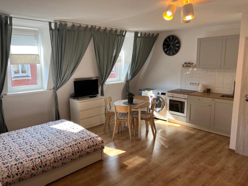 a bedroom with a bed and a table and a kitchen at Grand Central Apartments in Katowice