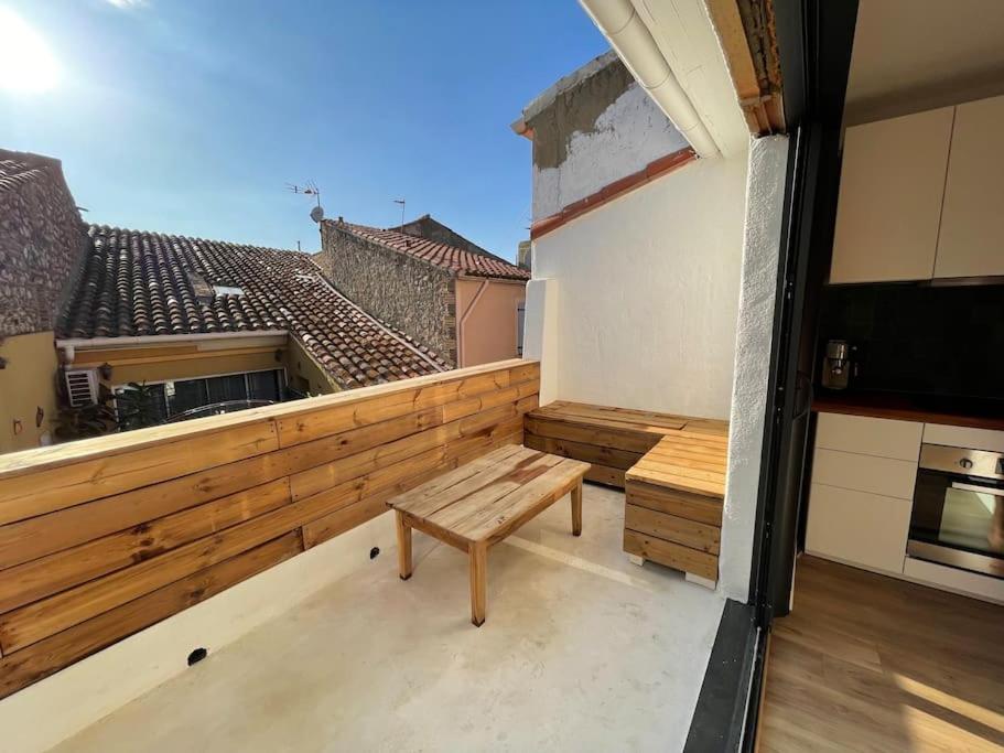 a balcony with a wooden bench and a table at Superbe duplex à 5 min de la plage in Torreilles