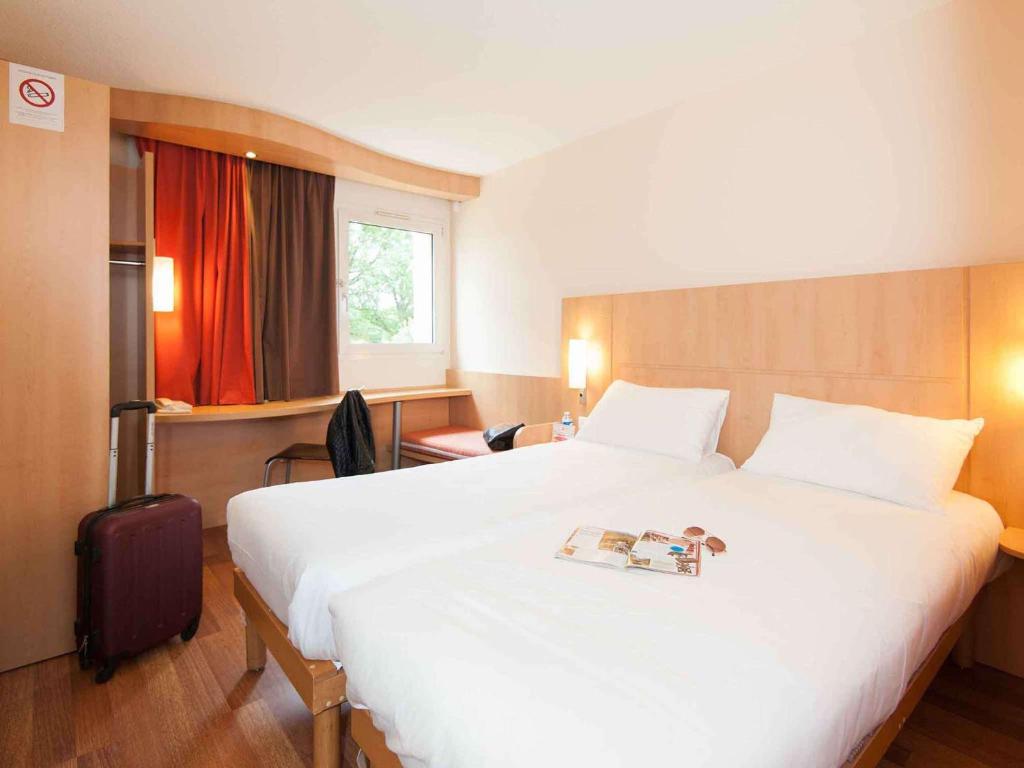 een hotelkamer met een groot bed met een boek erop bij ibis Avallon in Magny