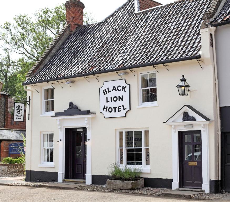 ein weißes Gebäude mit einem Schild mit einem schwarzen Löwen in der Unterkunft Black Lion Hotel in Little Walsingham